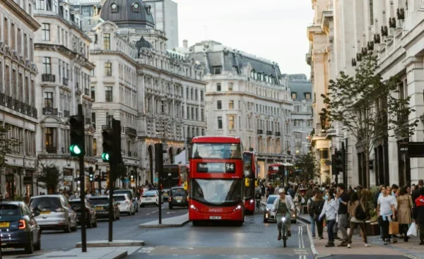 A bustling London street scene featuring iconic red double-decker buses and historic architecture.