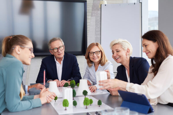 A group of professionals discussing ESG certification in an office setting with architectural models.