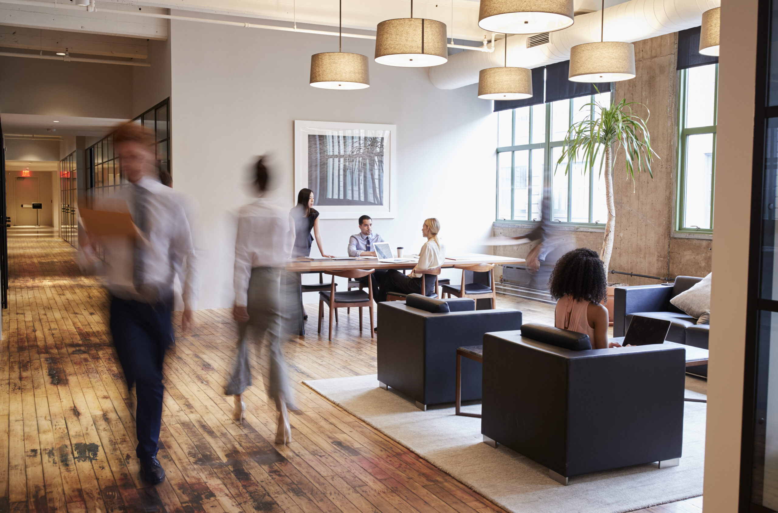 Business professionals working in a modern, luxury office space with wooden floors and comfortable seating.