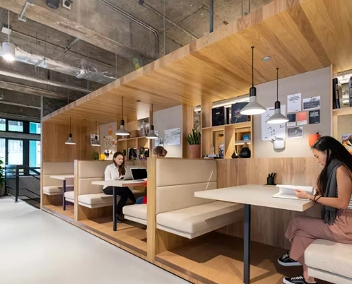 Modern office space with wood accents and people working in booth seating areas.