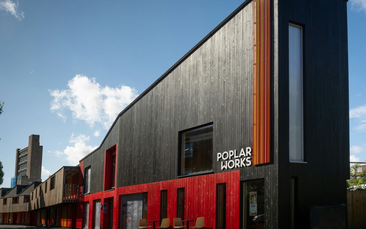 The image shows the modern architectural facade of Poplar Works on Abbott Road in London.