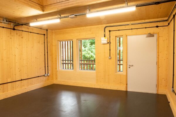 Interior of a wooden room with three windows and a door at Abbott Road 384, London.