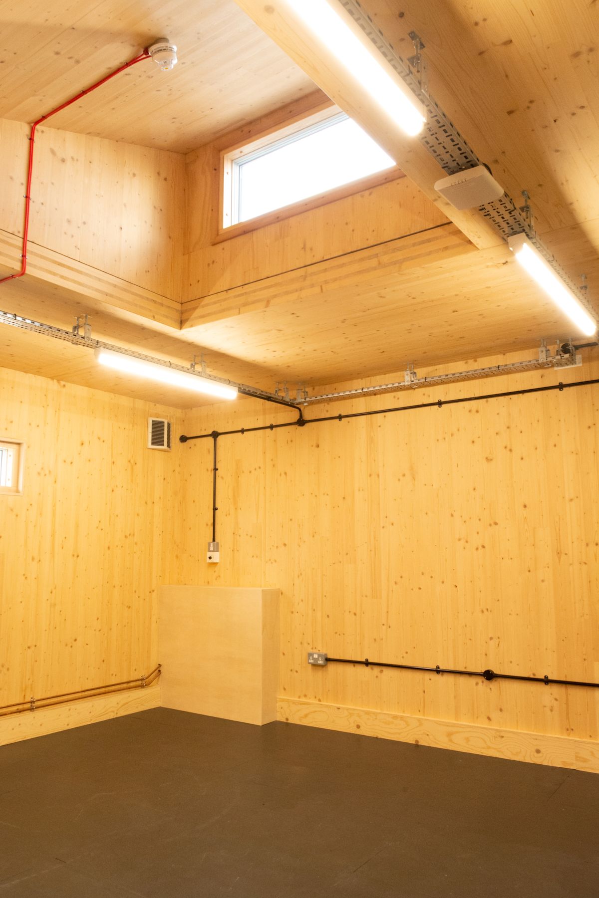 A wooden-interior room with exposed wiring and fluorescent lighting at Abbott Road 384, London.