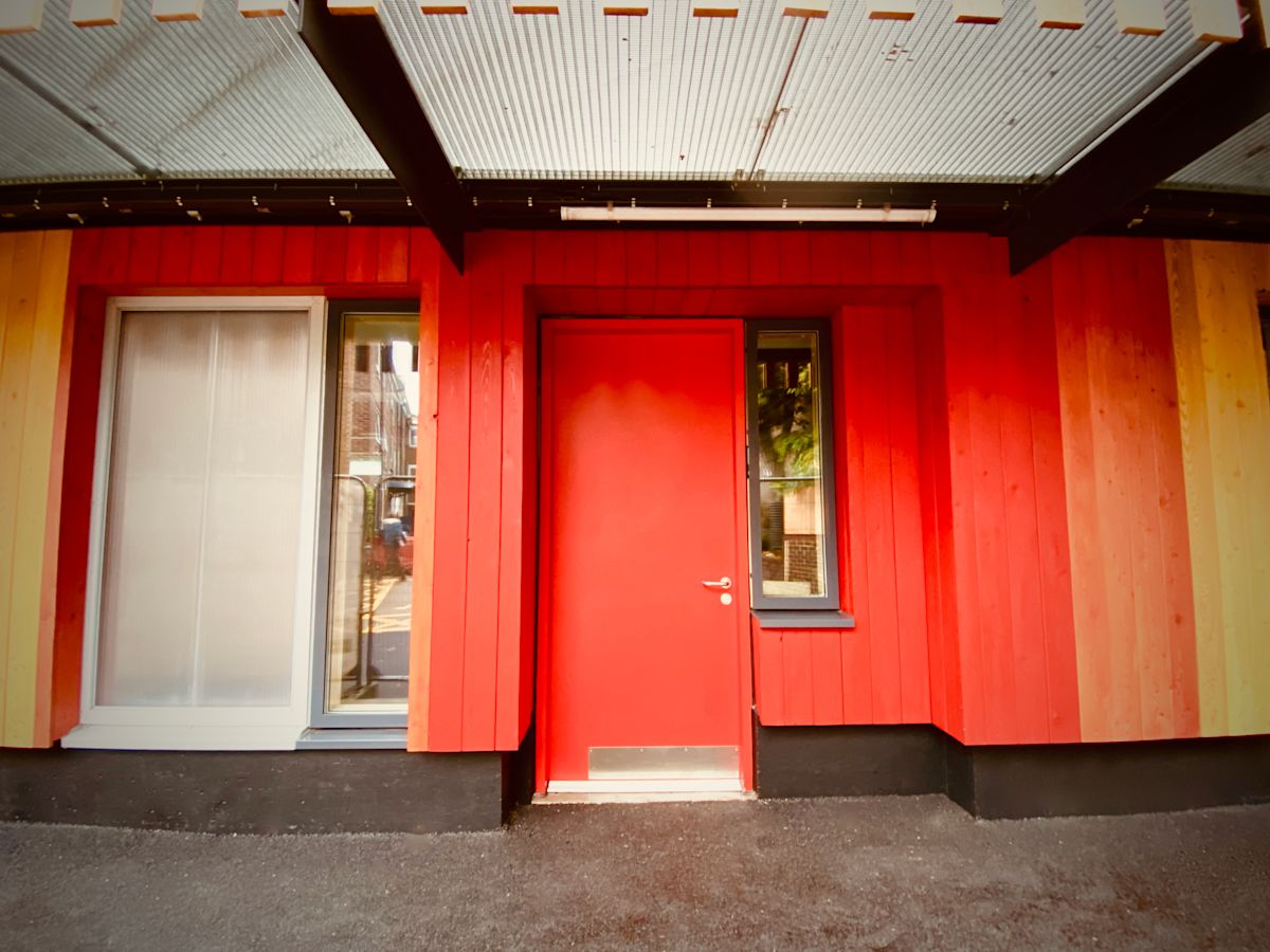 A vibrant red door and wooden facade at 384 Abbott Road, London.