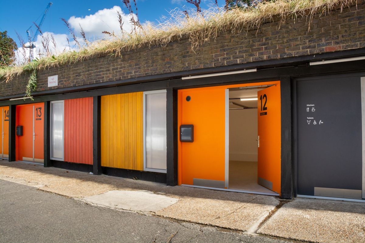 Colorful industrial units with orange and yellow doors along Abbott Road, London.