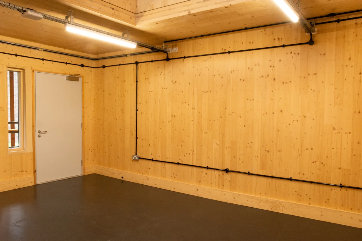 An empty room with light wood paneling and a closed door on Abbott Road 384, London.