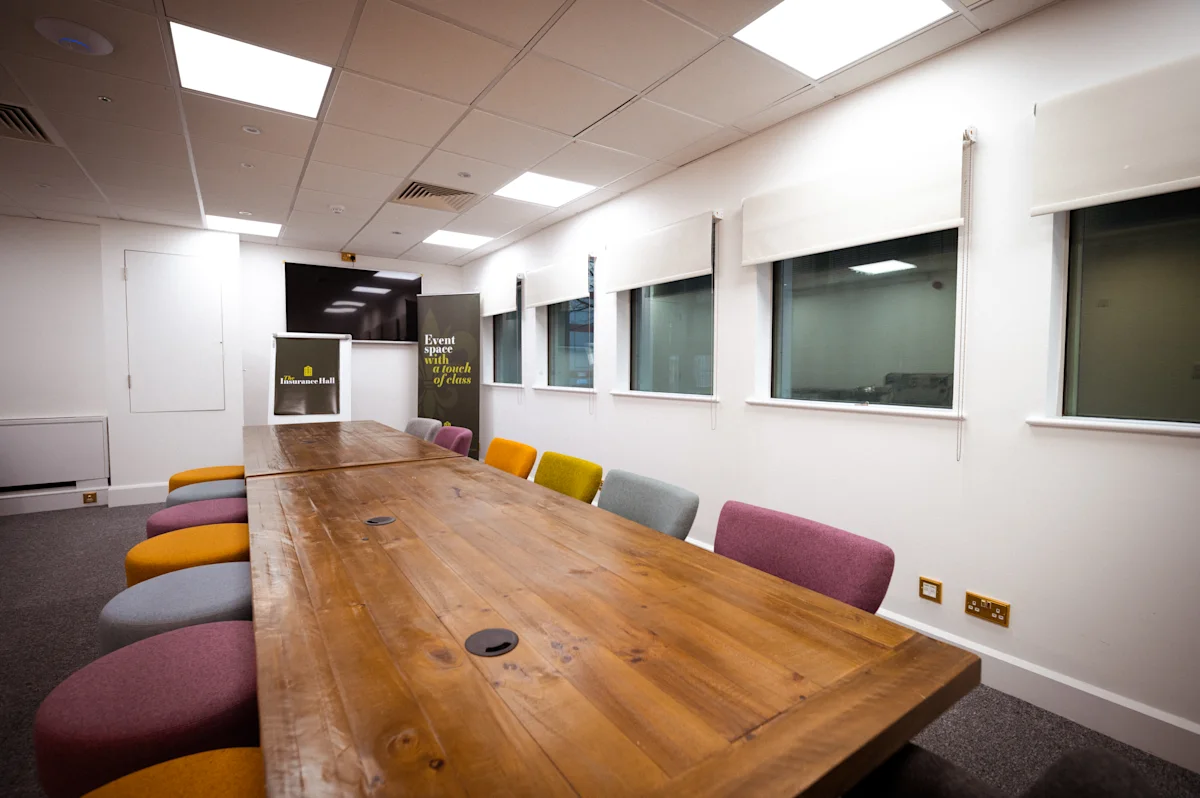 Meeting room with colorful chairs and a wooden table at Aldermanbury 21, London.