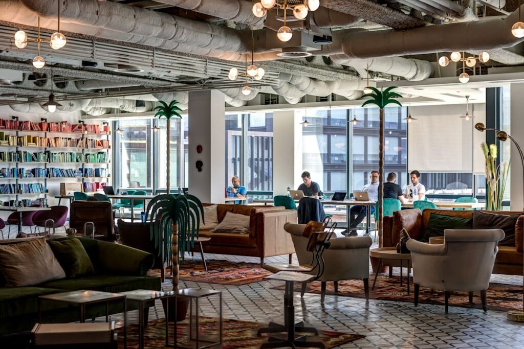 A modern co-working space with colorful bookshelves and people working on laptops at Appold Street 9, London.