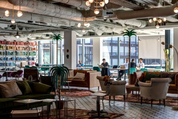 A modern co-working space with colorful bookshelves and people working on laptops at Appold Street 9, London.