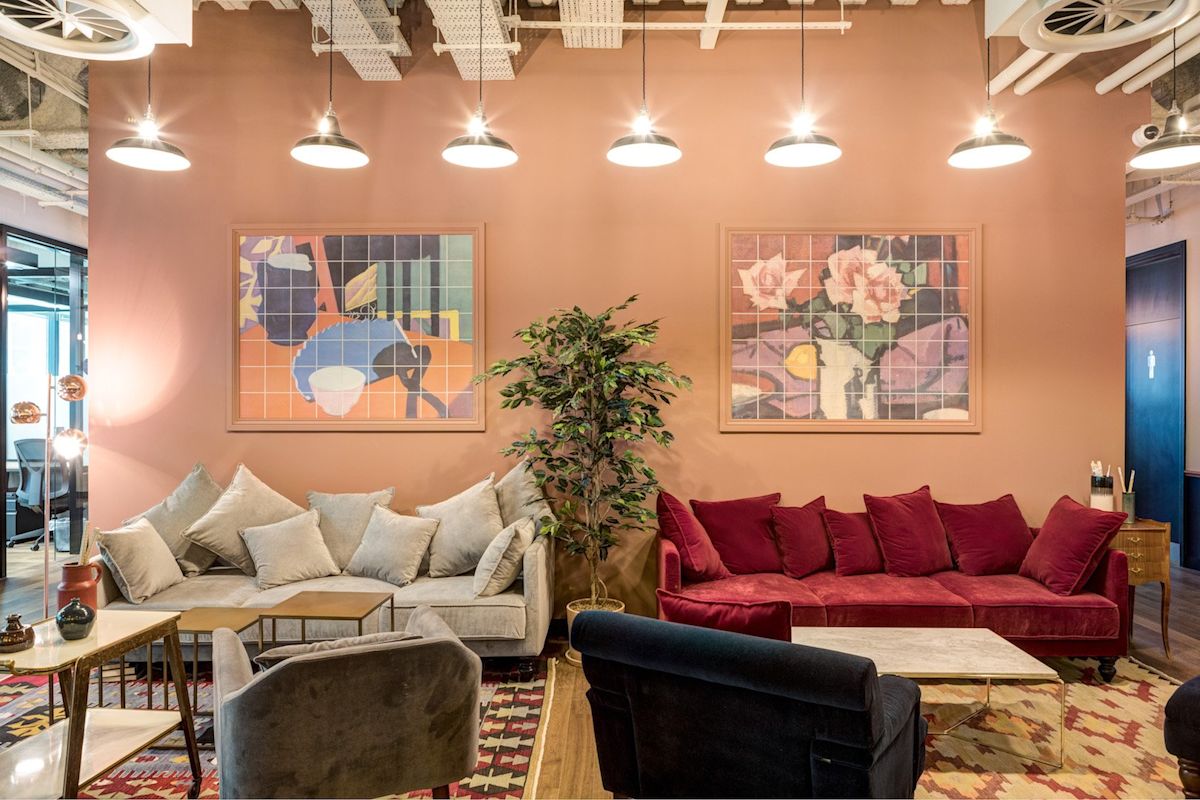 A cozy office lounge area in Appold Street 9, London, featuring colorful artwork, plush sofas, and soft lighting.