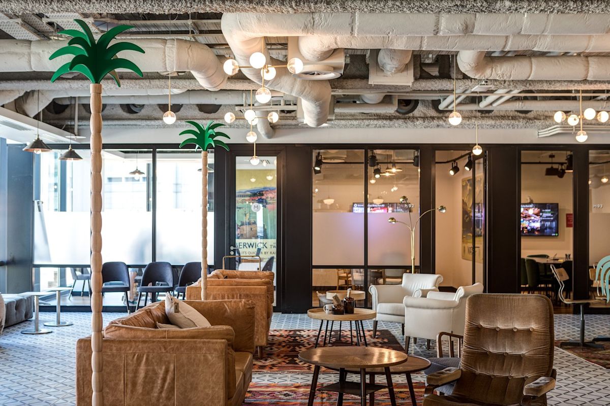 Modern office lounge with eclectic furniture and tropical decor elements.