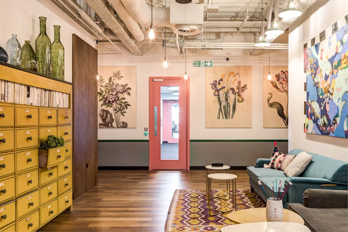 A stylish and colorful office interior on Appold Street, featuring a pink door, floral artwork, and eclectic decor.