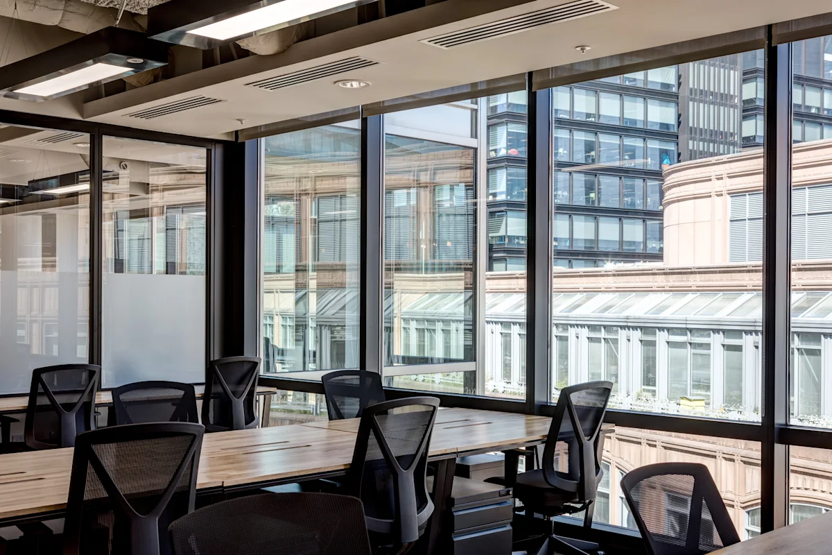 A modern office space with a view of surrounding buildings through large windows.