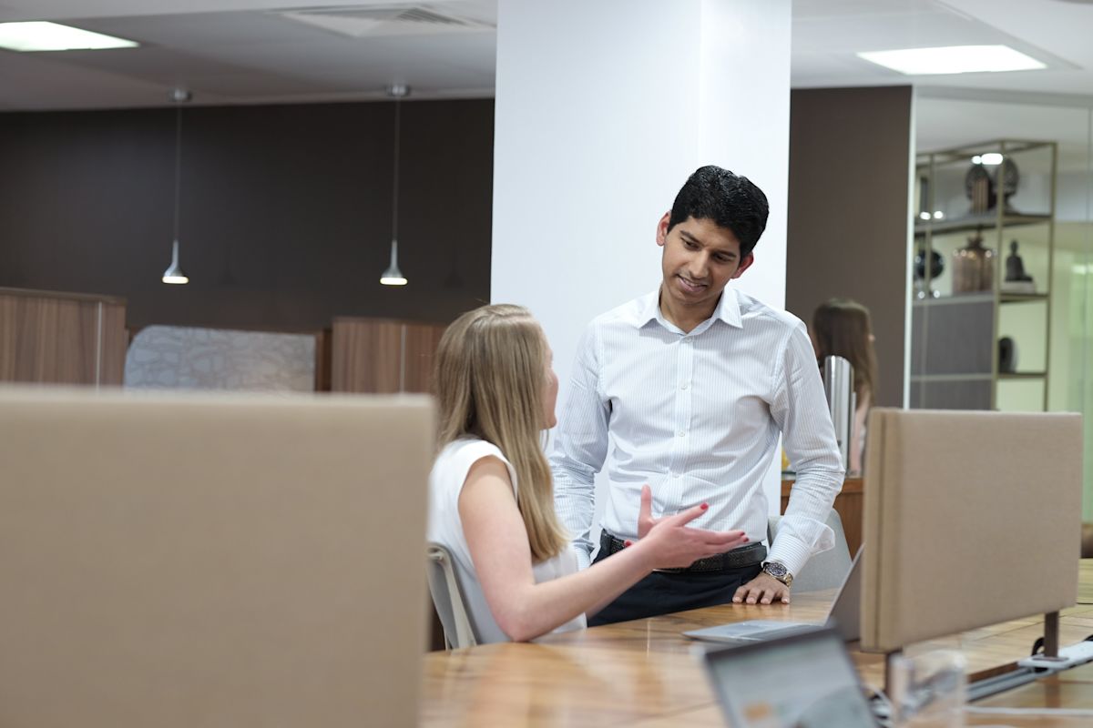 Two people having a discussion in a modern office setting.