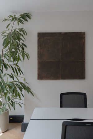A modern office space with a large potted plant, abstract wall art, and minimalist furniture.
