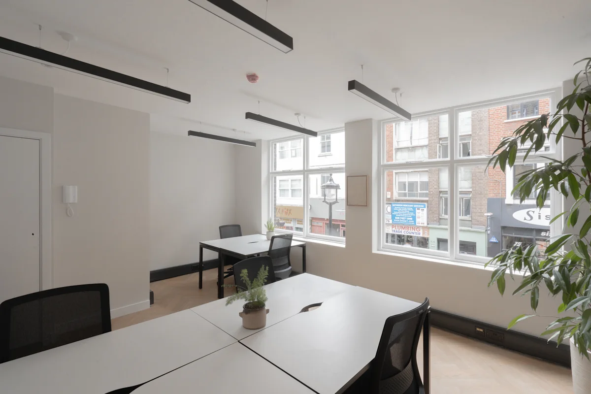 A bright office space with desks, chairs, and large windows overlooking Berwick Street, London.