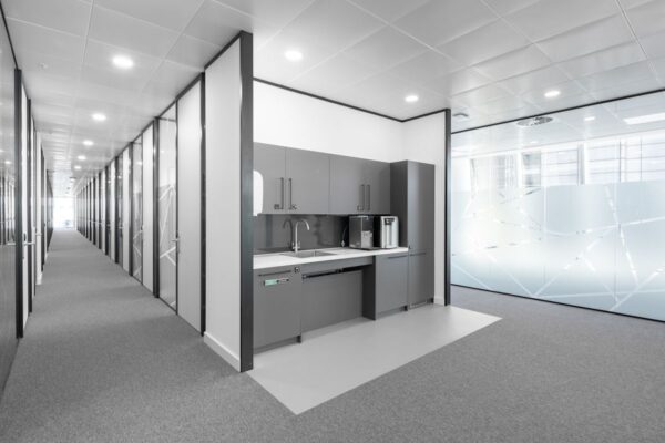 A modern office corridor at Bishopsgate 100 in London, featuring a small kitchenette with gray cabinets.