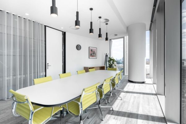 A modern conference room with a long white table and yellow chairs at 100 Bishopsgate, London.