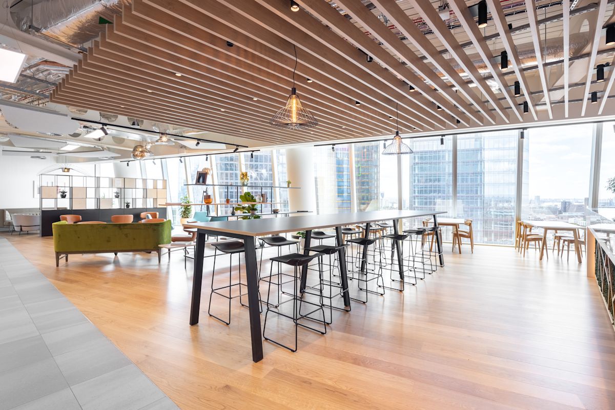 Modern open-plan office space in Bishopsgate 100 London with high tables, chairs, and large windows.