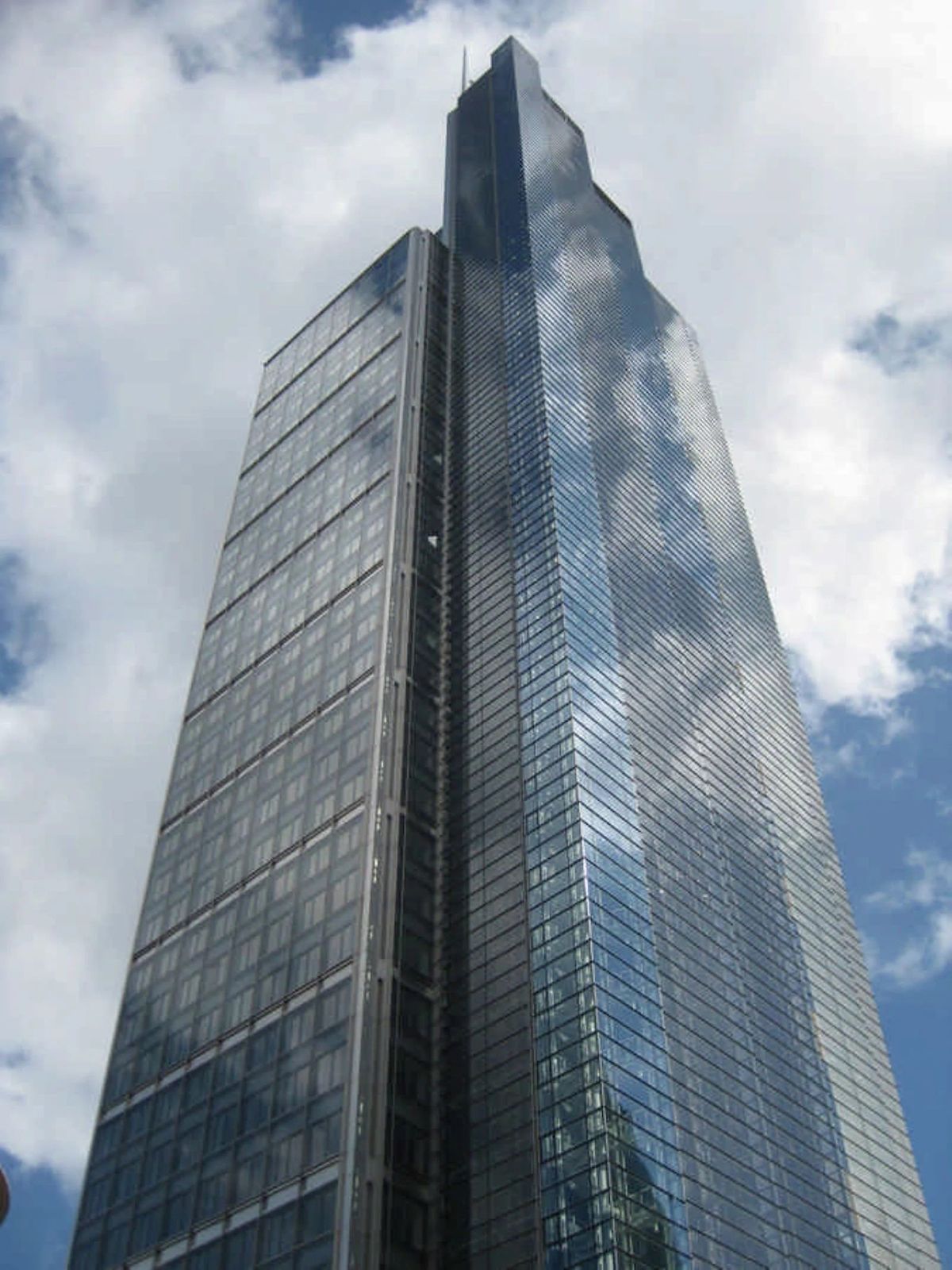 A tall, modern glass skyscraper known as Bishopsgate 110 London against a cloudy sky.