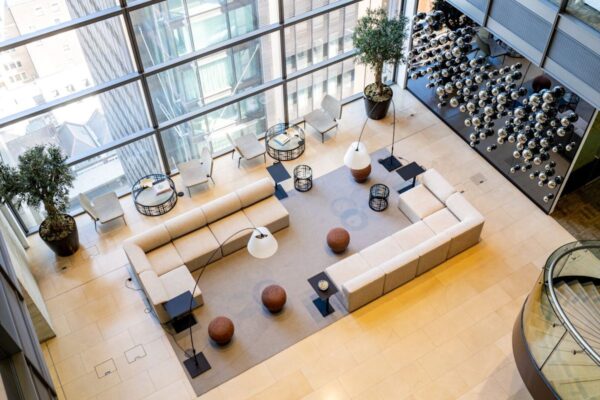 A modern office lounge area with beige sofas, glass walls, and decorative hanging spheres at Bishopsgate 110, London.