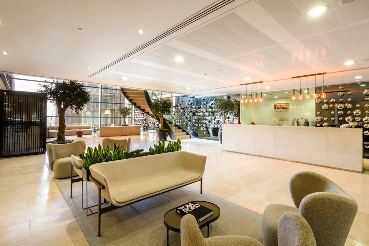 A modern office lobby at Bishopsgate 110, London, featuring stylish seating, a plant display, and a winding staircase.
