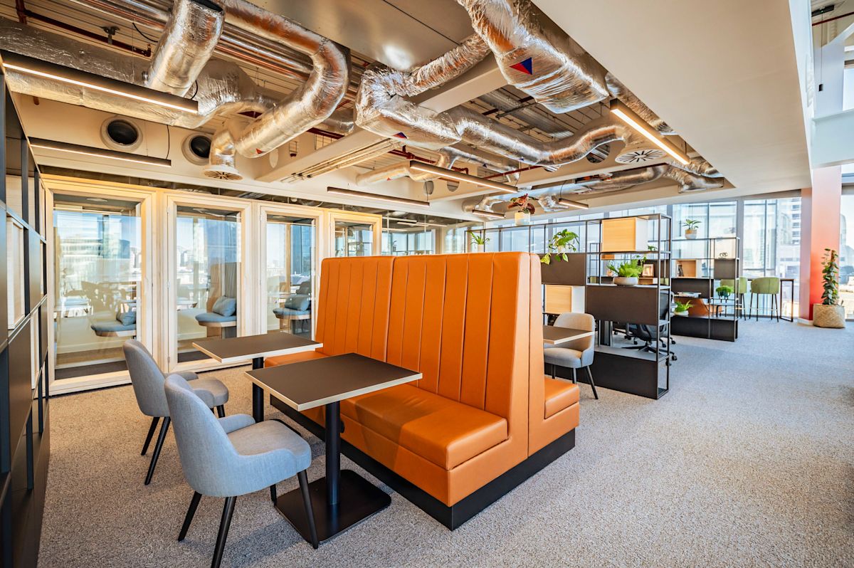 Modern office interior at Bishopsgate 22, London, featuring orange booth seating and contemporary decor.