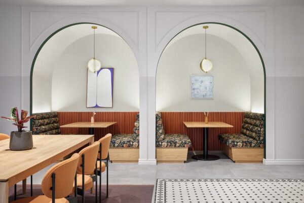 Modern café interior at Bishopsgate 22, London, featuring cozy archway seating with floral cushions and pendant lighting.