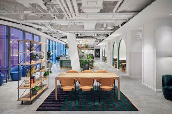 Modern office interior at Bishopsgate 22, London, featuring a long table, colorful chairs, and decorative shelving.