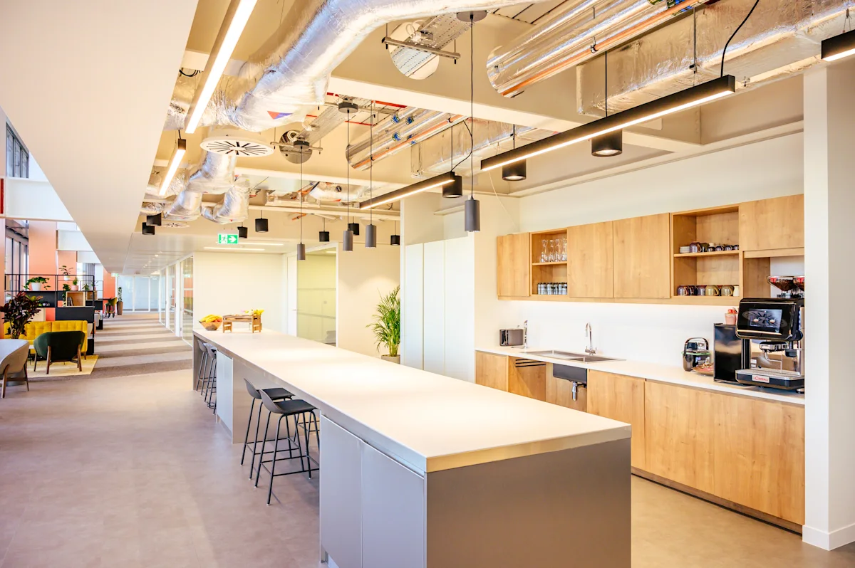 A modern office kitchen and break area at Bishopsgate 22 in London, featuring a long countertop and wooden cabinets.