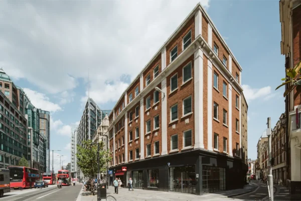 Street view of the red-brick building at 222B Bishopsgate, London, with traditional double-decker buses in the background.
