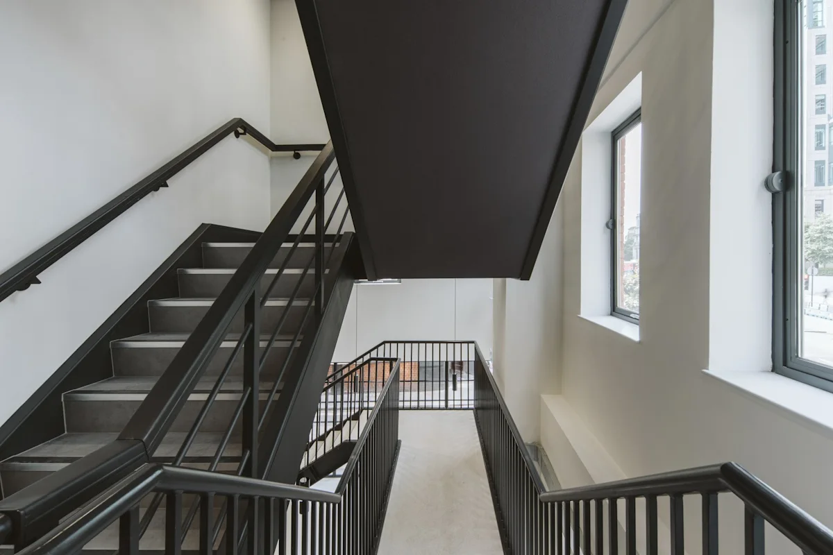 A modern interior stairway with black railings and two large windows at Bishopsgate 222 B, London.