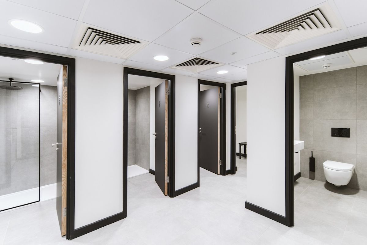 Modern public restroom with multiple toilet and shower stalls at Bishopsgate 222 B London.