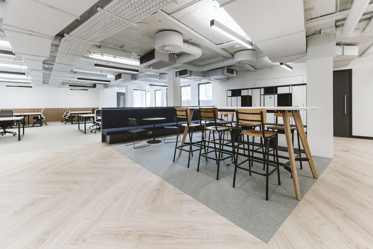 A modern office space in Bishopsgate 222 B, London, featuring workstations and a high table with chairs.