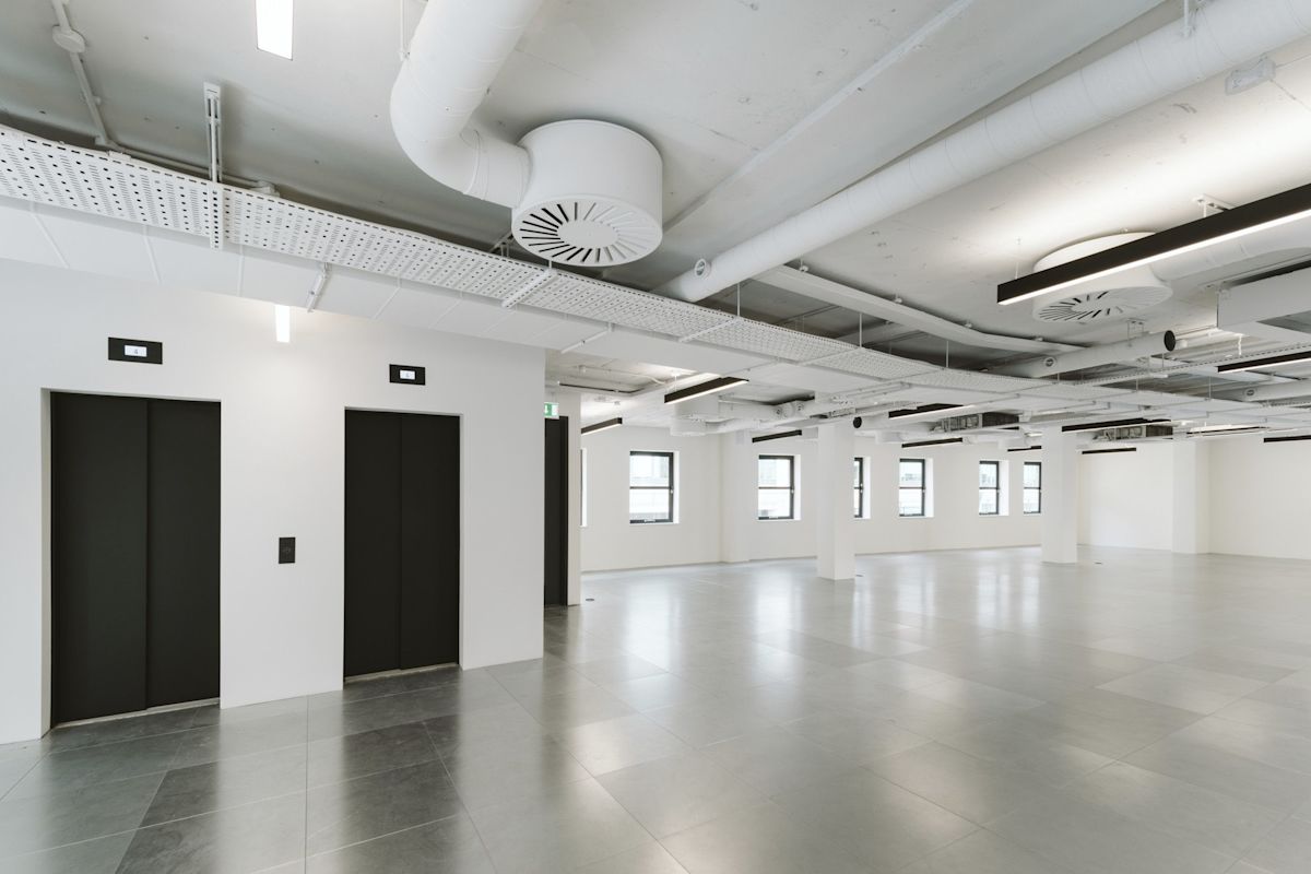 An empty, modern office space with elevators and large windows at 222 Bishopsgate, London.