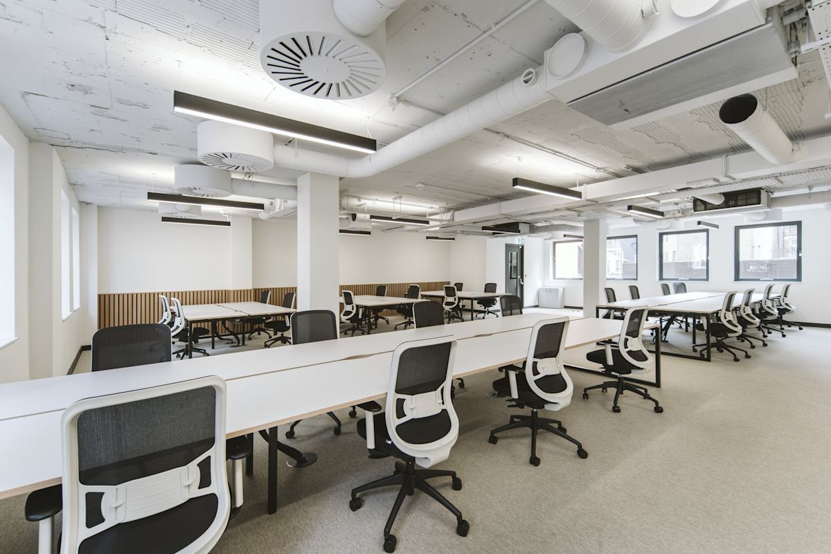 A modern, spacious office interior with multiple desks and ergonomic chairs.