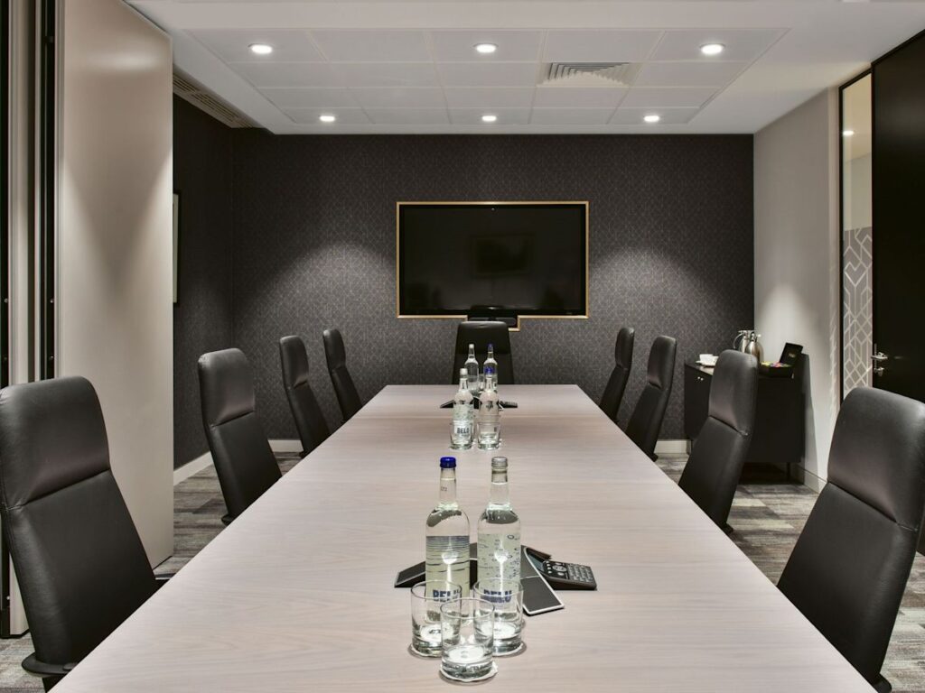 A modern conference room at Bishopsgate 288 in London with a long table, leather chairs, and a wall-mounted TV.