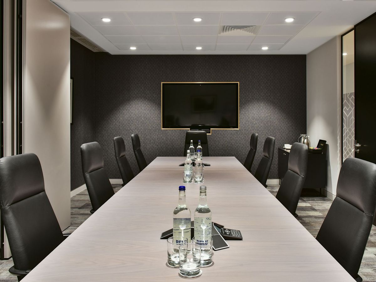 A modern conference room at Bishopsgate 288 in London with a long table, leather chairs, and a wall-mounted TV.