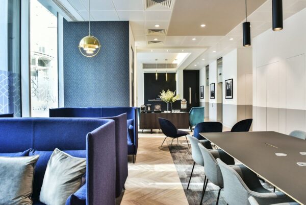 Modern office lounge area with blue seating and a meeting table at Bishopsgate 288, London.
