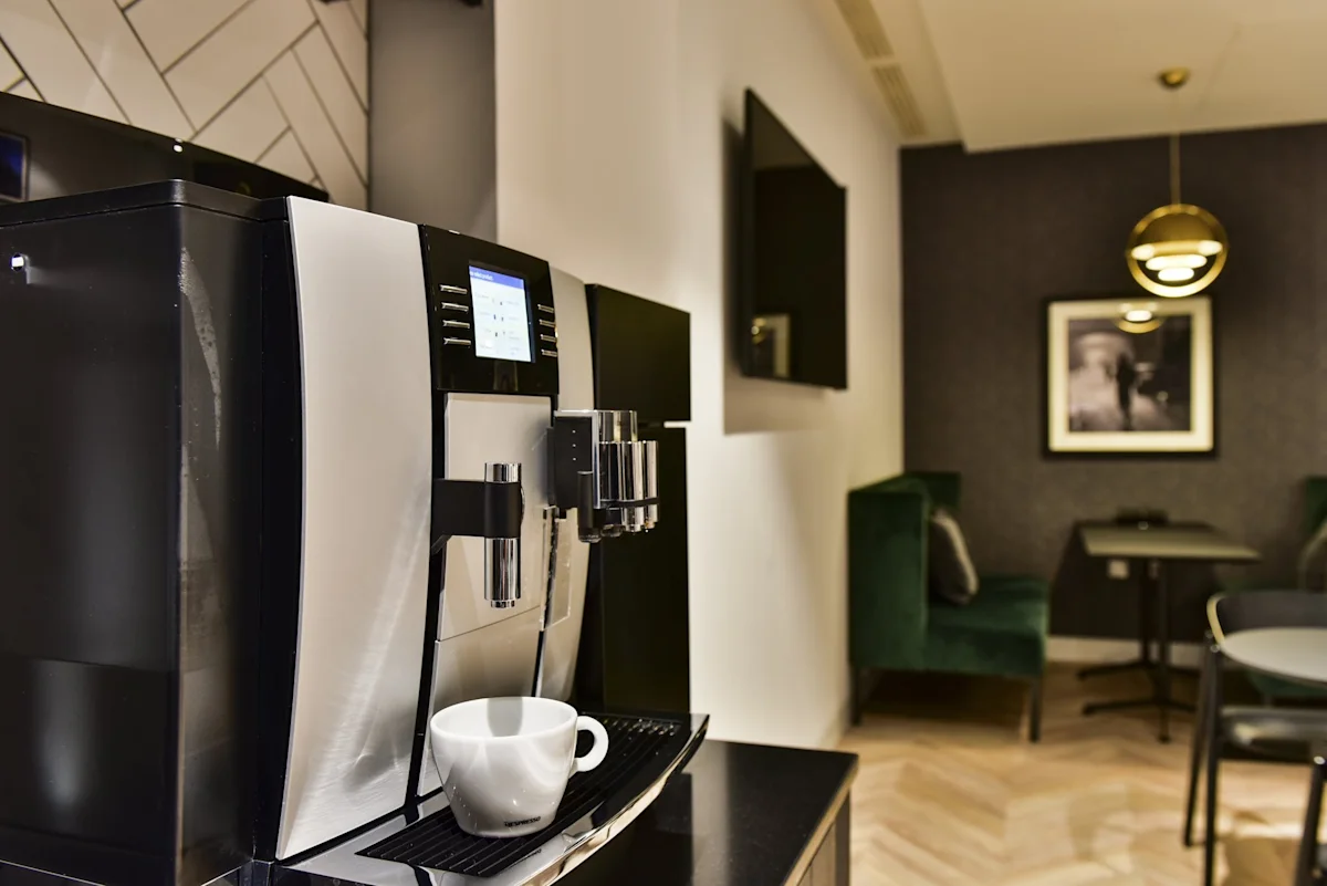 A modern coffee machine in a stylish office lounge with a seating area.