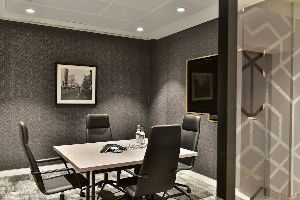 A modern meeting room with a table, four chairs, a photograph on the wall, and a television.