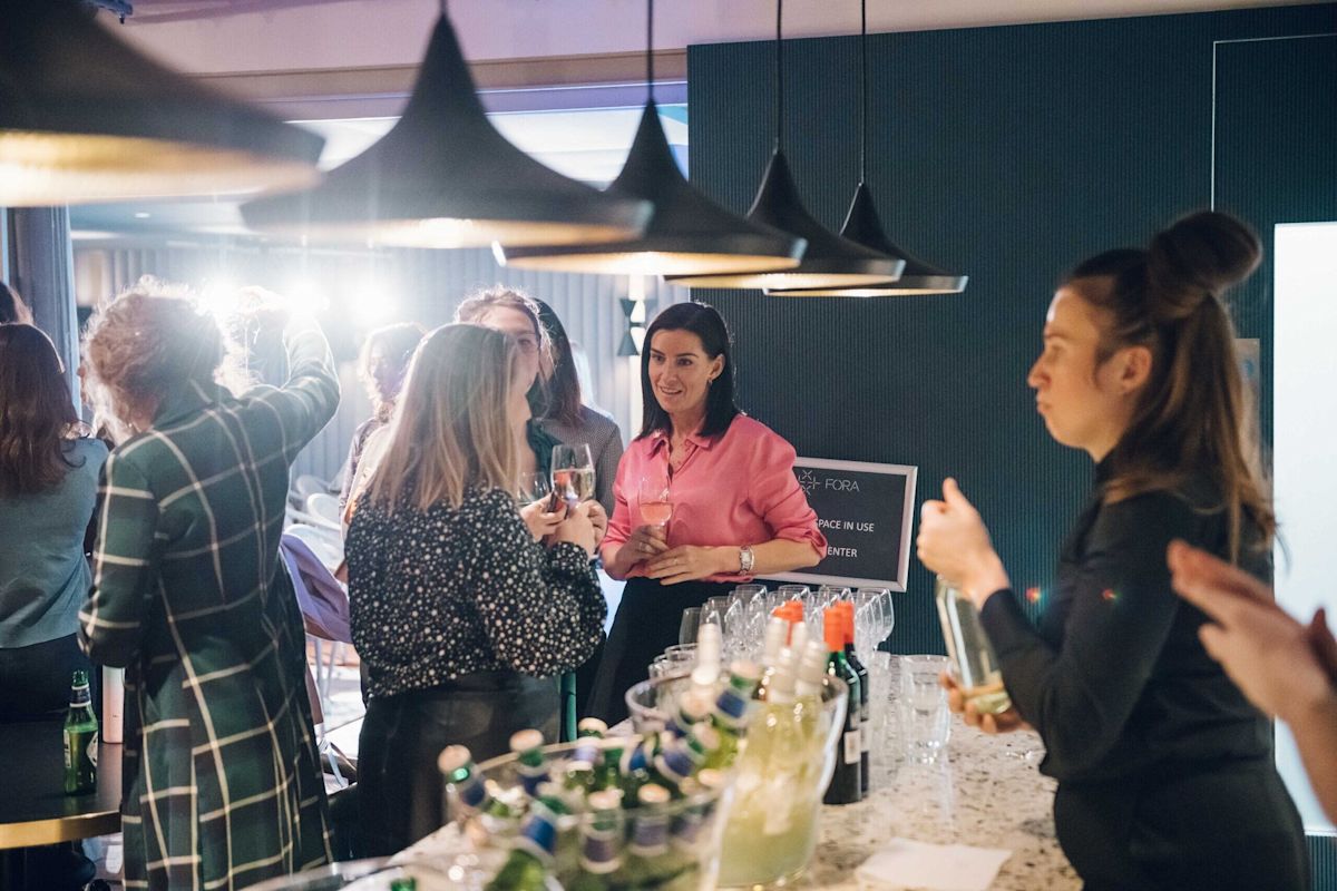 A group of people socializing and holding drinks in a modern indoor setting.