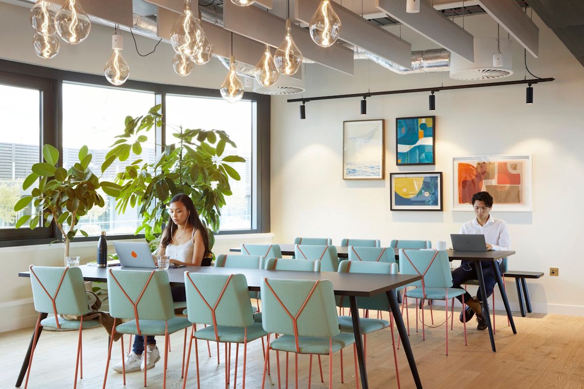 A modern office space at Broadwick Street 33 in London with people working on laptops at a communal table.