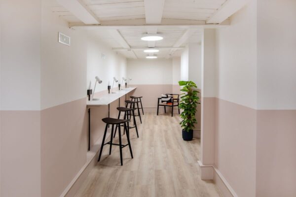 A modern workspace with bar stools, desk lamps, and a potted plant inside an office on Broadwick Street, London.