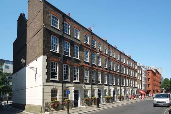 A row of historic brick buildings on Broadwick Street in London under a clear blue sky.