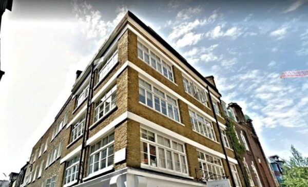 Corner view of a brick building on Broadwick Street, London, under a partly cloudy sky.