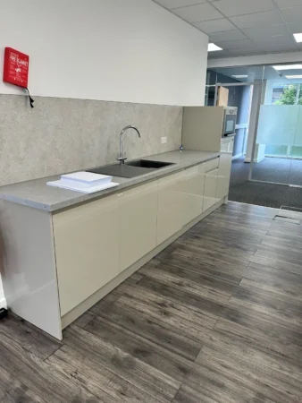 Modern office kitchenette with a sleek design and wood flooring.