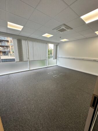 An empty office space with carpeted flooring and large windows at Cadmus Court Ground Floor, London.