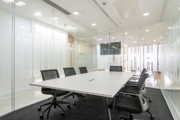 A modern conference room in Canada Square 1, London, with a long table, office chairs, and glass walls.