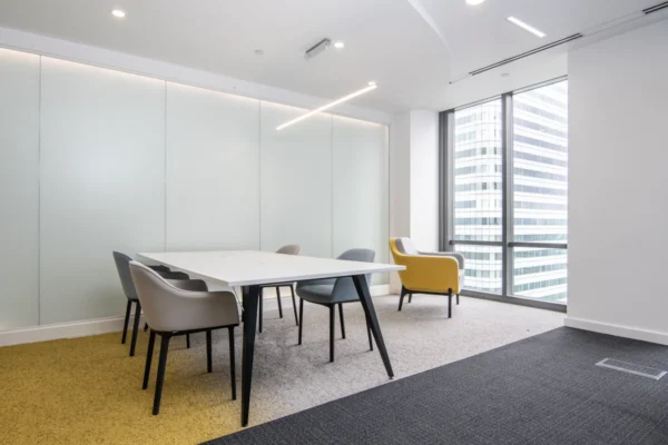 Modern meeting room with a large table, various chairs, and a window view of a tall building.